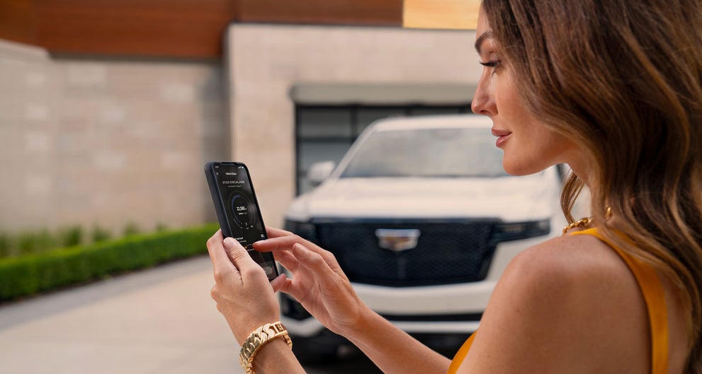 lady checking her mobile with a Cadillac vehicle background | Romain Cadillac in Evansville IN